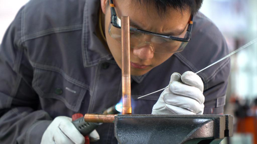 4月12日,在安吉技师学院的教学车间里,杨应政正在进行铜管焊接工艺的