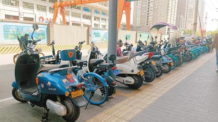 东门外的路边停放着多辆超标电动自行车