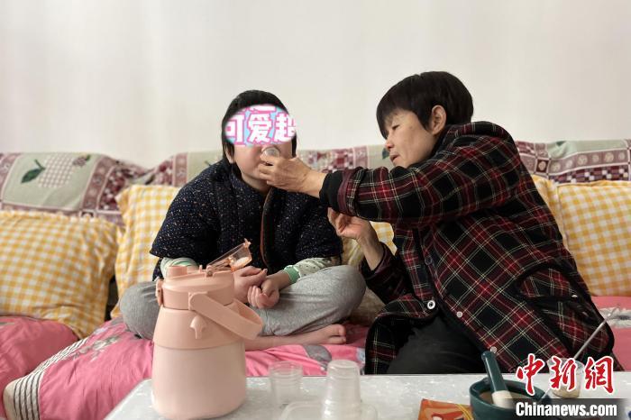 奶奶陈玉英给涵涵喂药 周星亮 摄