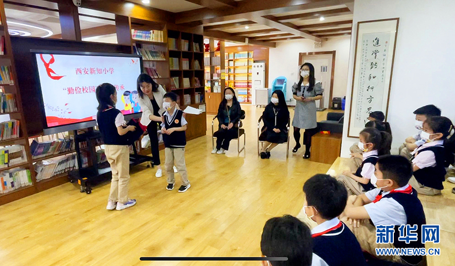 4月26日，在西安新知小学校服传承活动上，老师指导三年级的小学生将自己穿小的校服送到一年级的学弟手上。新华网 杨喜龙 摄