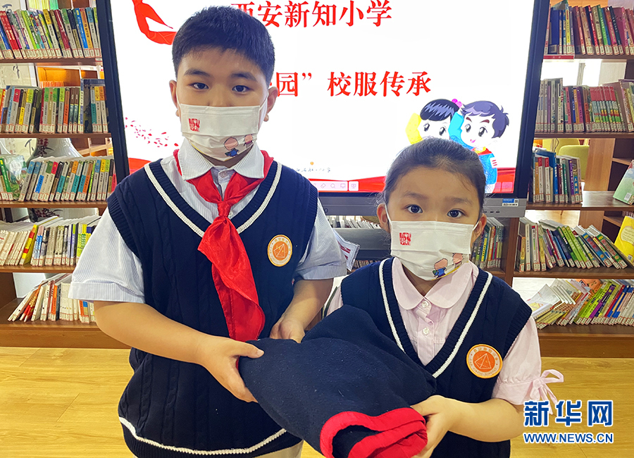 4月26日，在西安新知小学校服传承活动上，一位三年级的小学生（左）和一位一年级的小学生拿着校服合影留念。新华网 杨喜龙 摄