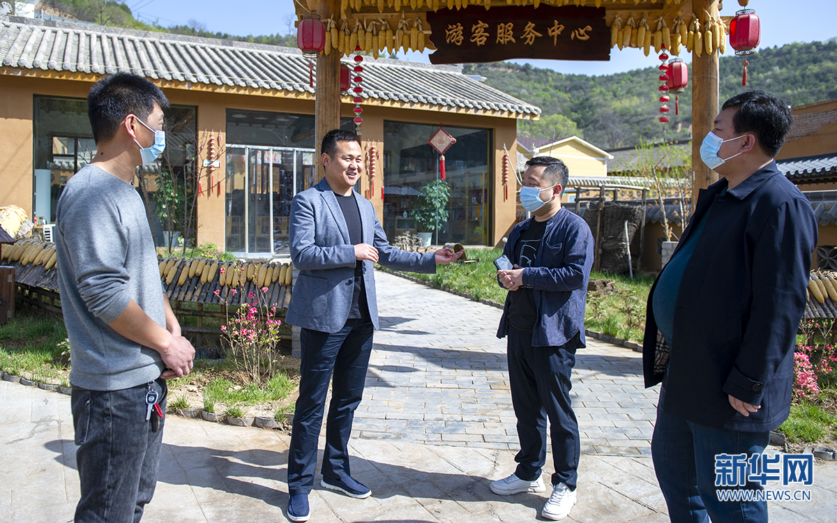 4月23日，黄龙县乡村振兴局工作人员董世凯（左二）介绍偏石村的发展情况。张云勇 摄