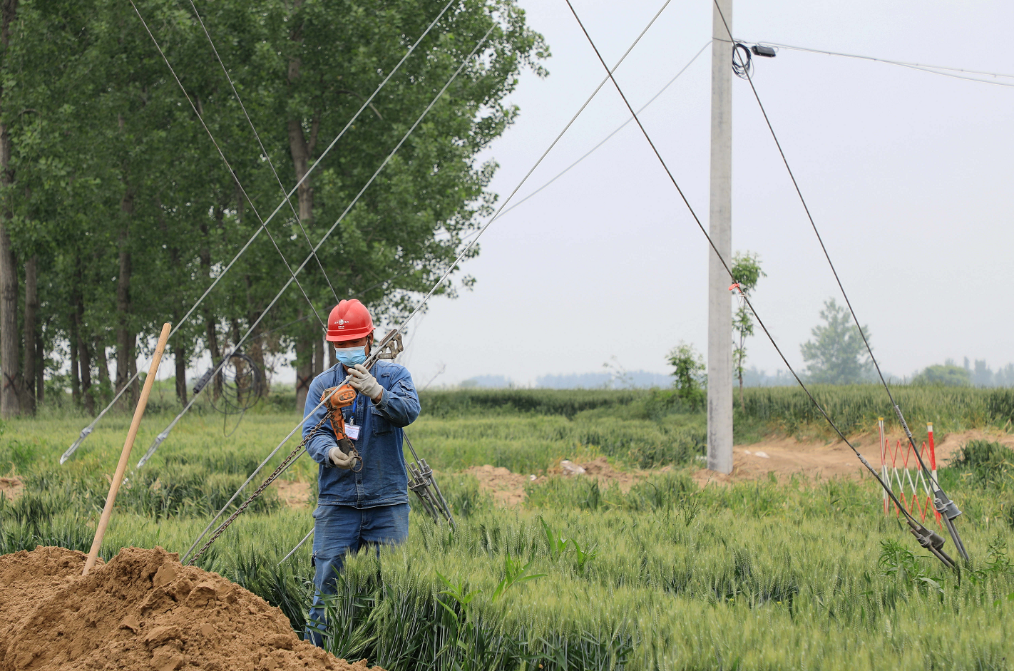 电力施工人员在迁建现场紧固拉线.徐浩然 摄