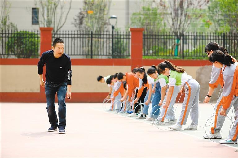 校长陶建文（左）给孩子们示范滚铁环动作