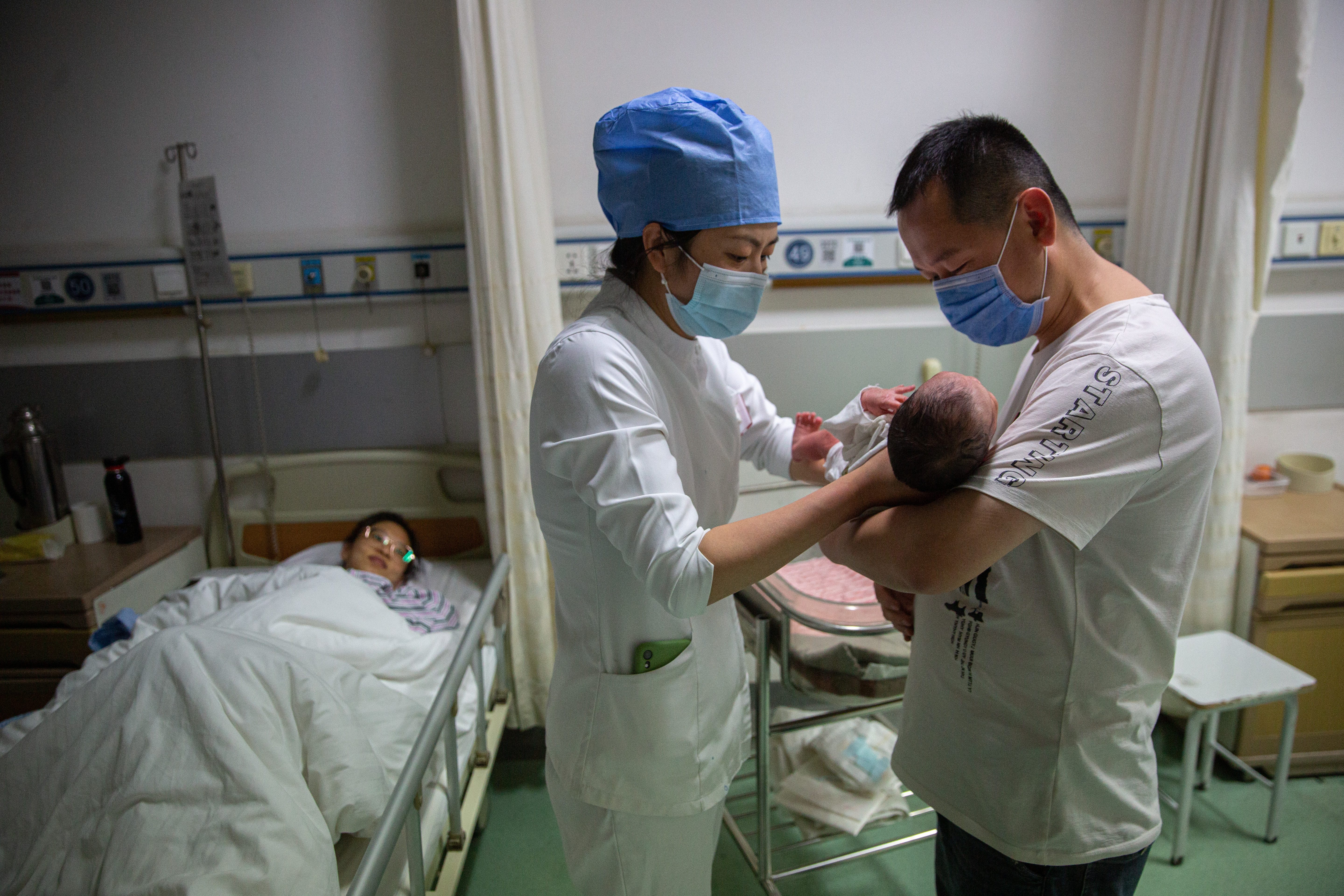 5月7日晚，北京大学首钢医院产科病房，护士张胜苗指导一名新生儿的父亲抱孩子。
