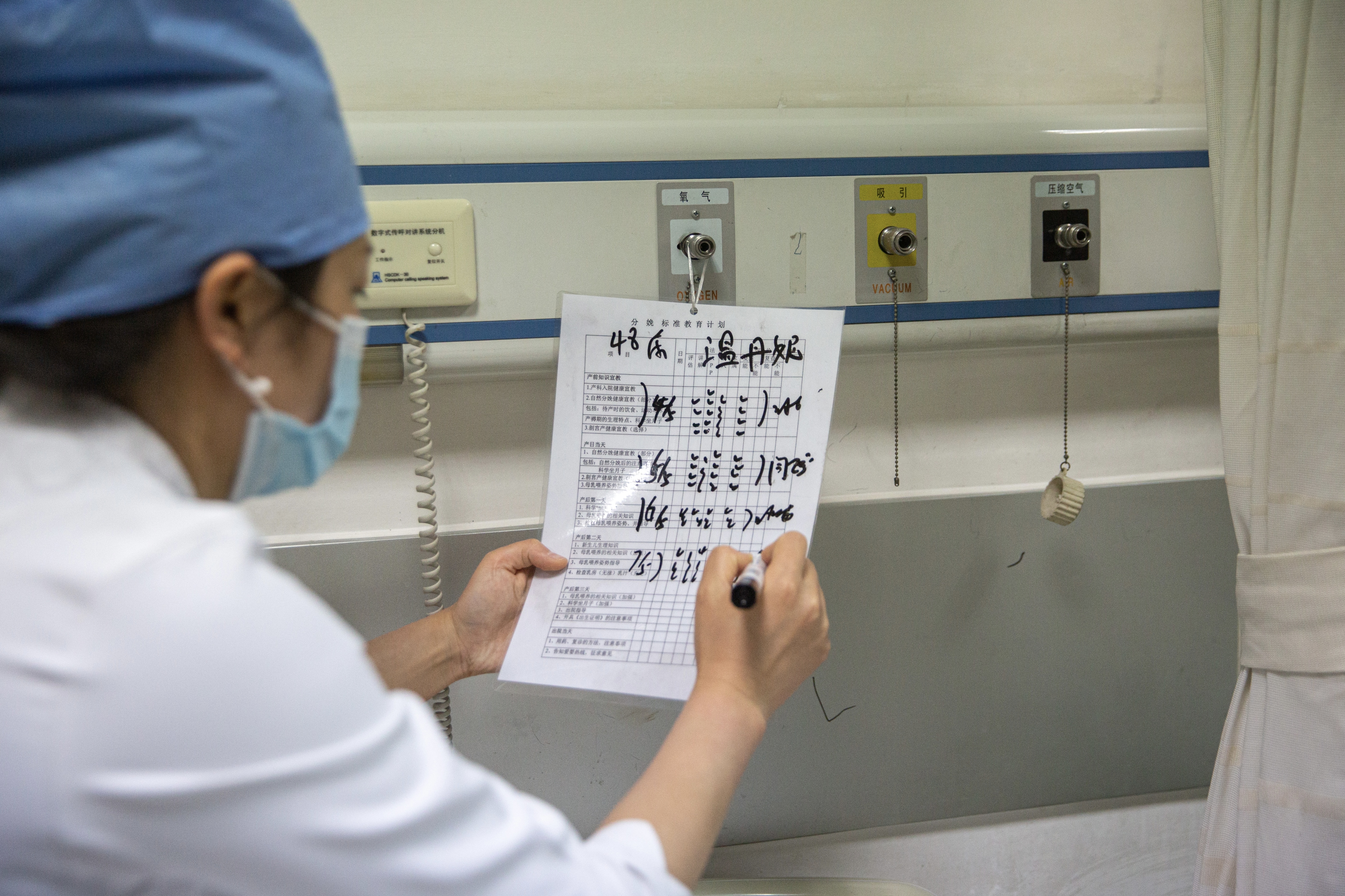 5月7日晚，北京大学首钢医院产科病房，护士张胜苗在填产妇床头的一份《分娩标准教育计划》。