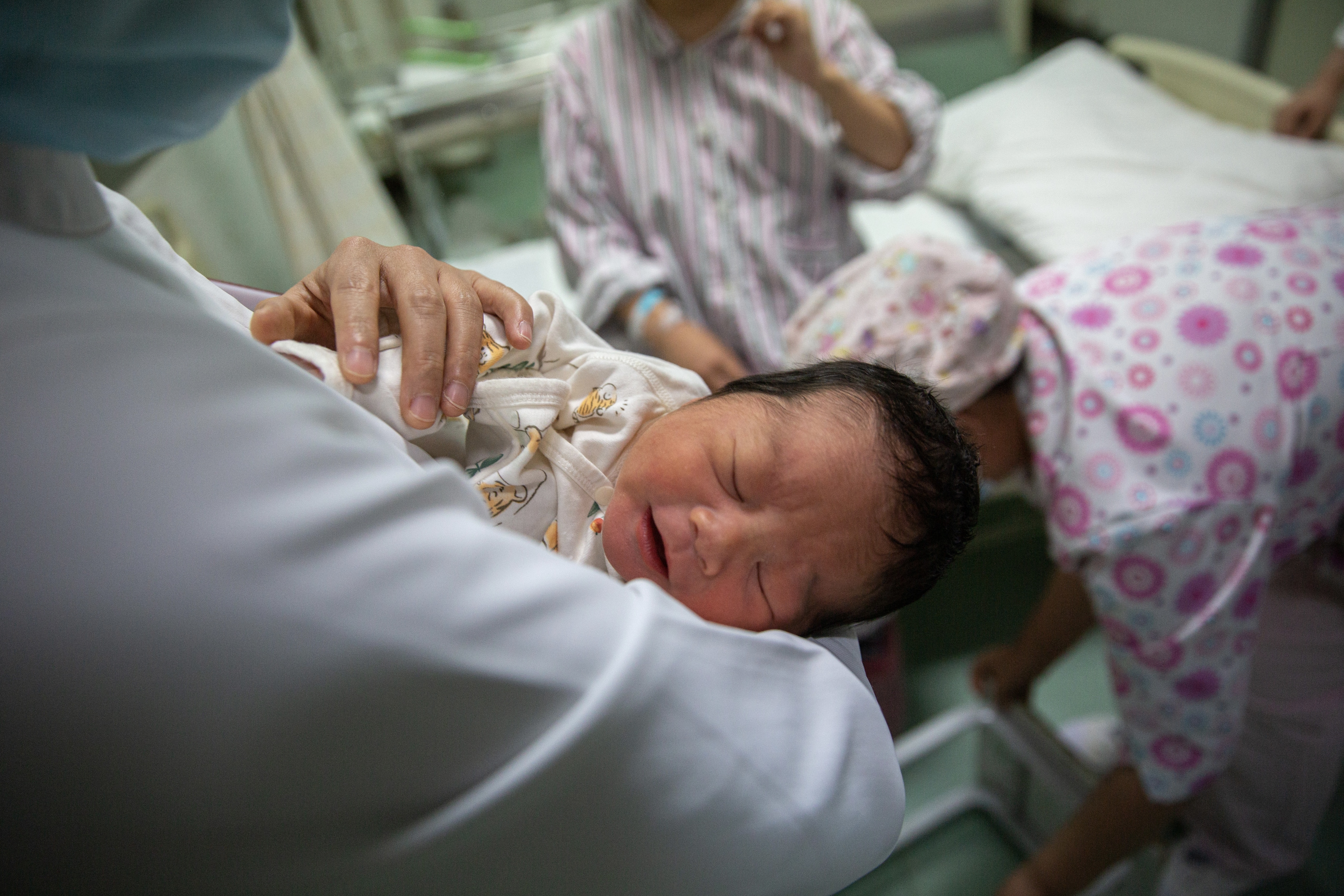5月7日晚，北京大学首钢医院产科病房，护士张胜苗抱着一名新生儿。