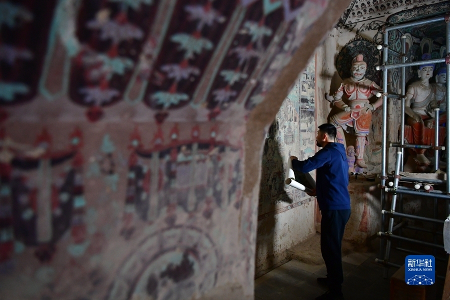 4月19日，在莫高窟第172窟，刘小同在对比临摹壁画的细节。新华社记者 杜哲宇 摄