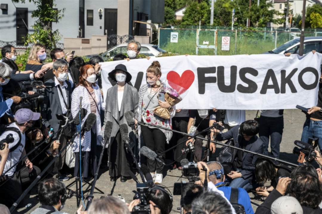 重信房子(中)在女儿及律师的陪同下会见媒体,现场有支持者拿著“我们爱(重信)房子”的横幅。图源:AFP