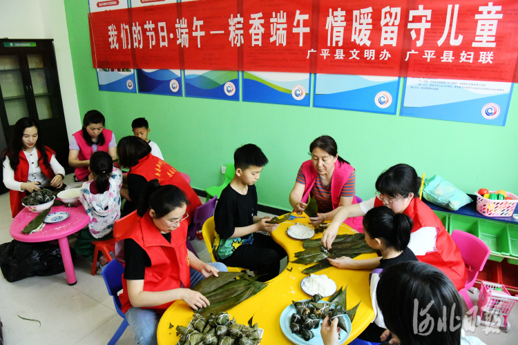 2022年5月28日，在河北省邯郸市广平县南韩村镇唐庄村，志愿者们在陪留守儿童一起包粽子。