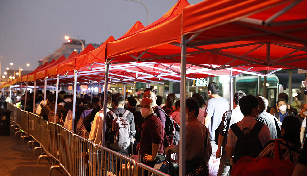 5月29日，在红色雨棚下等候进入安置点的人群。