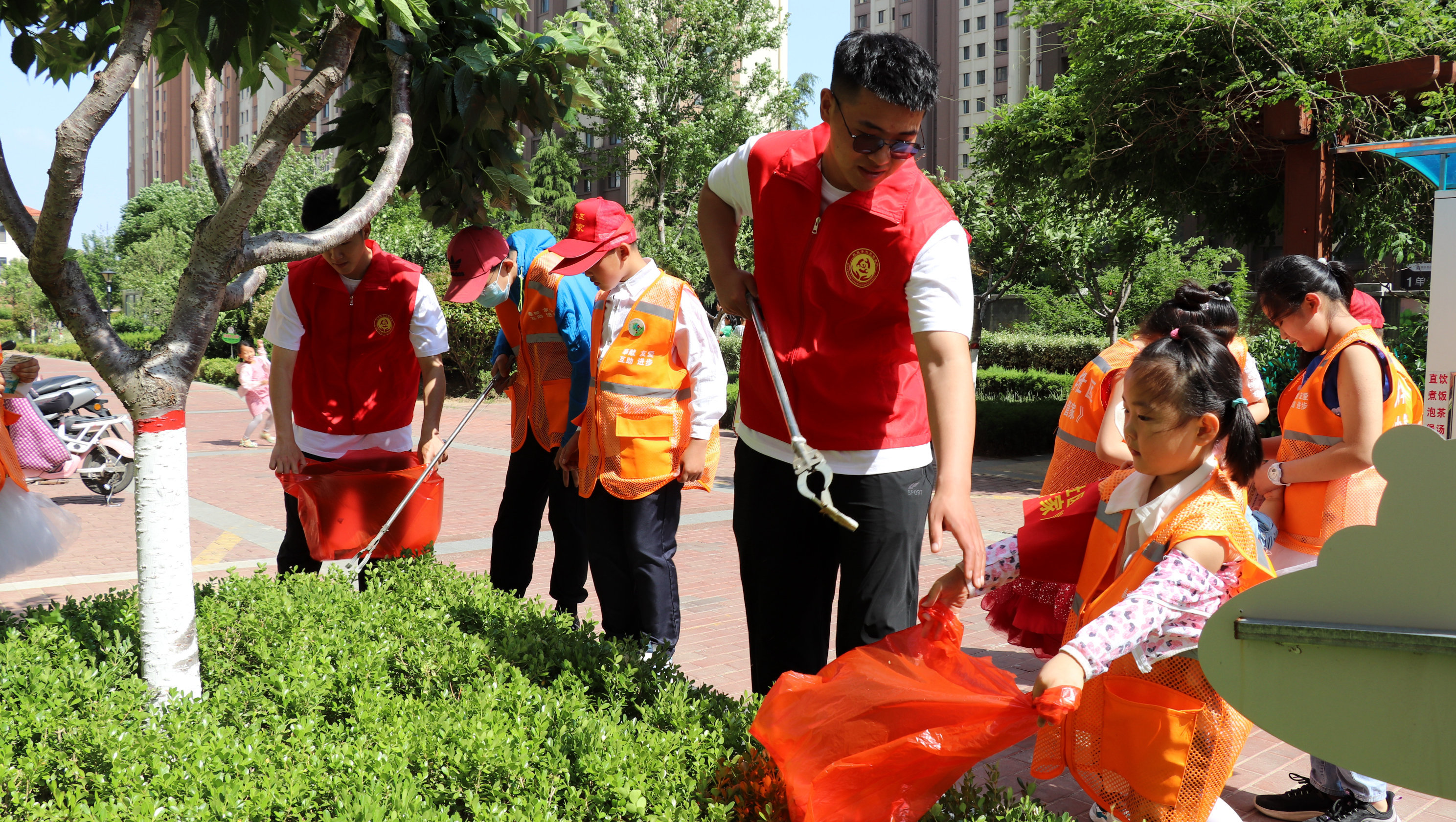 中建八局四公司“红扳手”志愿服务队和大华社区“小管家”们一起捡拾绿化带内垃圾