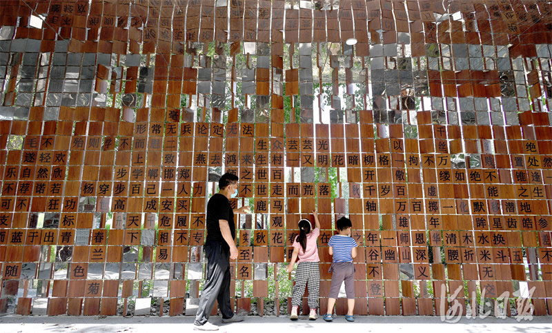 2022年5月29日，市民在河北省邯郸市复兴区福兴园“成语墙”前做成语游戏。