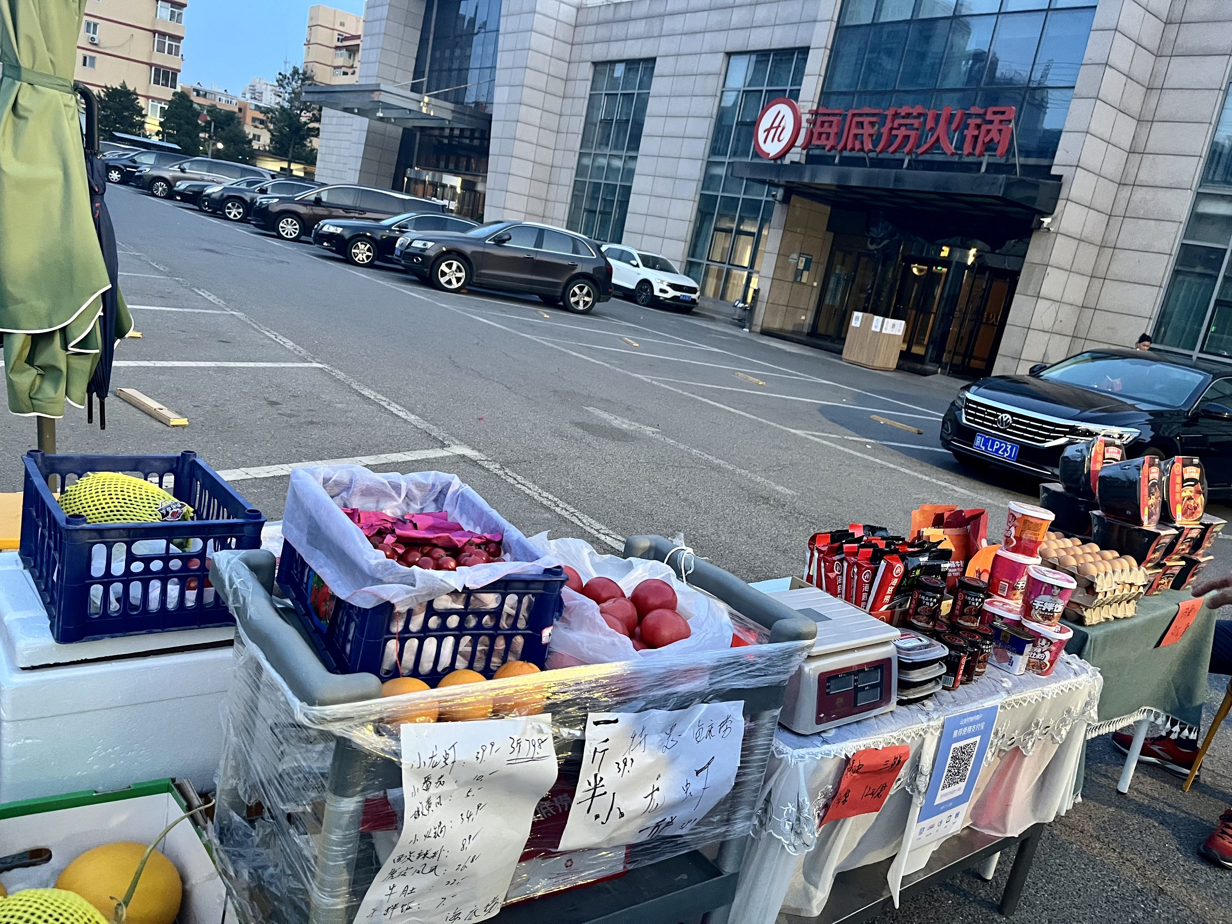 5月23日傍晚，海底捞万丰桥店停车场入口。摊位上摆满了果蔬、鸡蛋、火锅底料、方便食品等。新京报记者 吴淋姝 摄