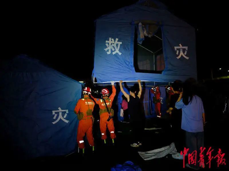6月1日晚，四川雅安宝兴县七一初级中学体育场安置点，当地年轻人协助消防员一起搭帐篷。程雪力/摄