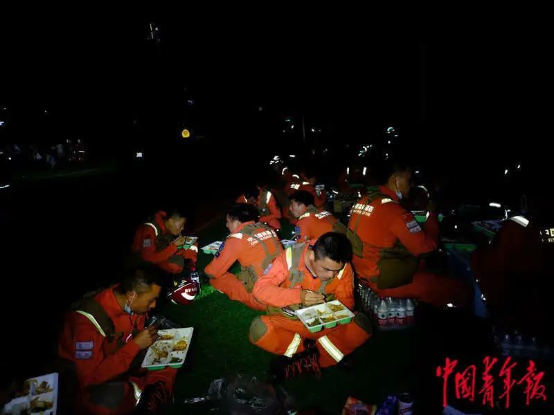 6月1日晚，四川雅安宝兴县七一初级中学体育场安置点，消防员正在吃盒饭。程雪力/摄