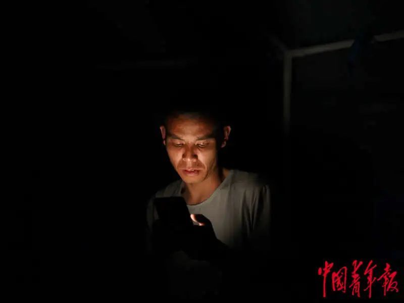 6月1日晚，四川雅安宝兴县七一初级中学体育场安置点，一名正在看手机的男子。程雪力/摄