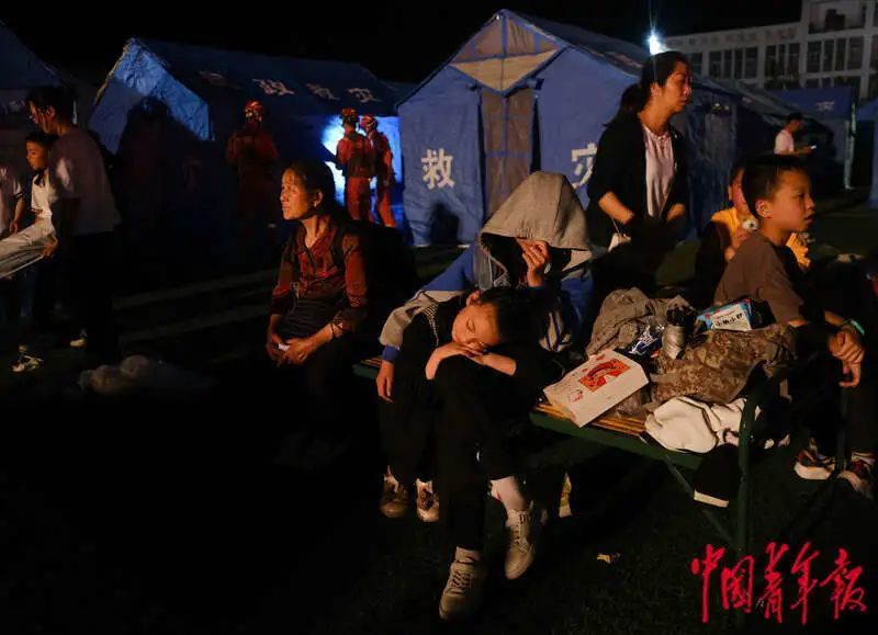 6月1日晚，四川雅安宝兴县七一初级中学体育场安置点，一名小女孩在家人腿上睡着了。程雪力/摄