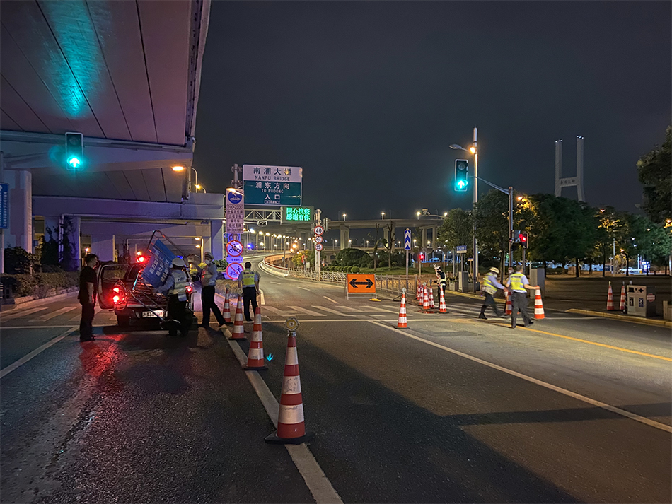 2022年5月31日23时20分，上海浦西，通往浦东的南浦大桥瞿溪路上引桥上，民警正在拆除路障设施。澎湃新闻 乐浴峰 图
