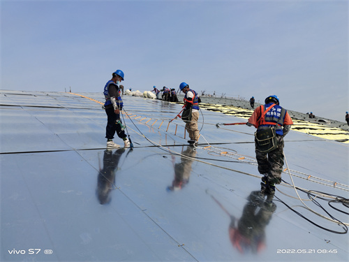 施工人员在西安国际足球中心金属屋面上挂设绳梯