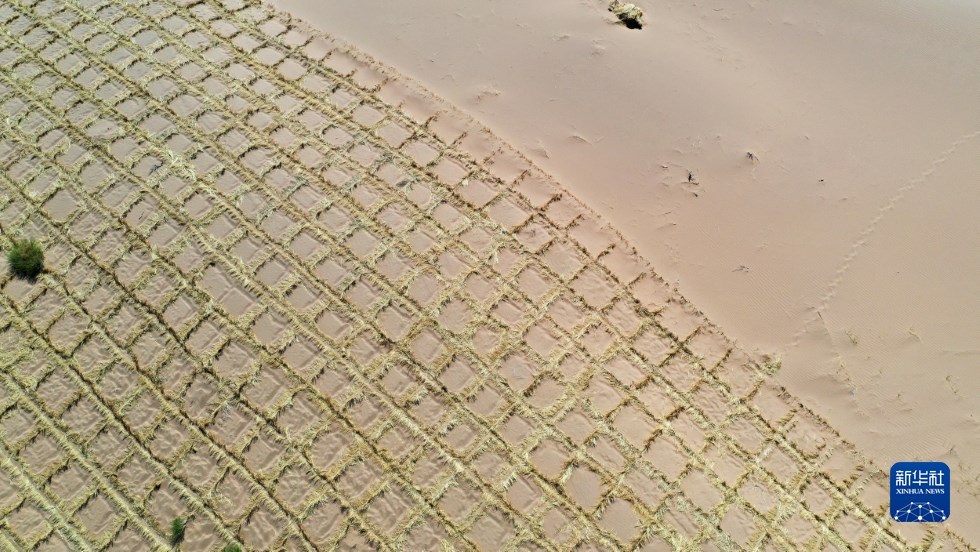这是武威市凉州区邓马营湖治沙区域部分铺设完草方格沙障的沙漠（6月16日摄，无人机照片） 新华社记者 陈斌 摄