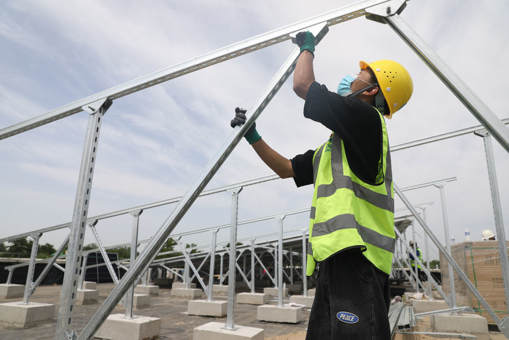 在河北省高碑店市新城镇加录幼儿园屋顶，中国电建工作人员正在安装光伏板。 马凯摄