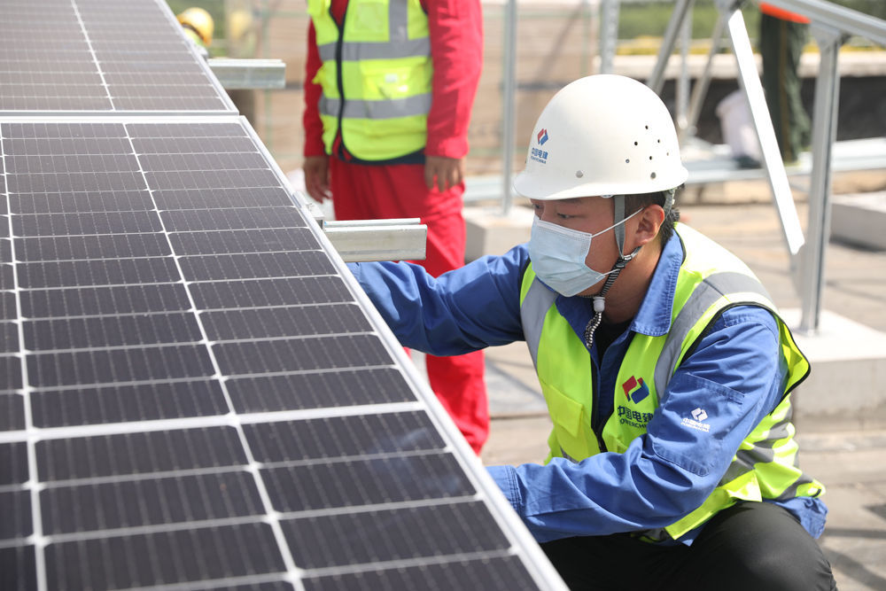 在河北省高碑店市新城镇加录幼儿园屋顶，中国电建工作人员正在安装光伏板。 马凯摄