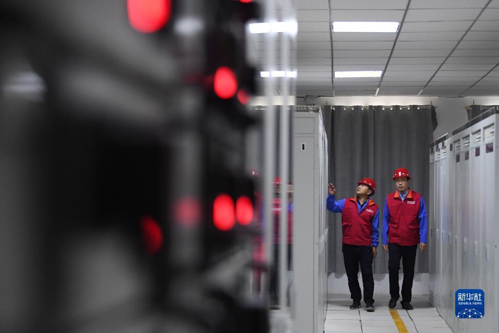 全景监控系统项目经理孙宁(左)和同事在华能集团西坡光伏电站机房内查看设备运行情况(6月13日摄) 新华社记者 陈斌 摄