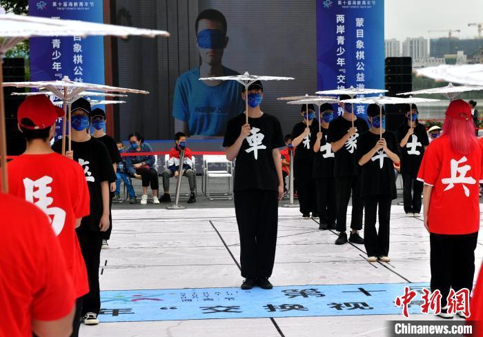 志愿者和在榕台湾青少年撑着有“车”“马”“炮”字样的油纸伞扮棋子,在棋盘上依棋手指令移动。 吕明 摄