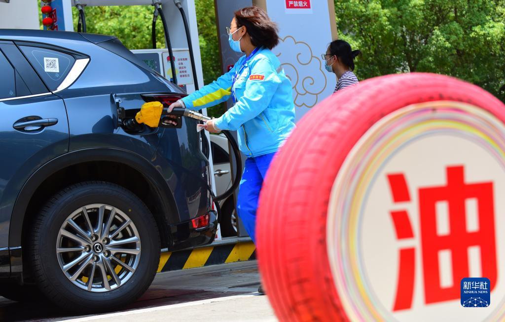 6月14日，江苏省无锡市一加油站工作人员给汽车加油。新华社发（还月亮 摄）