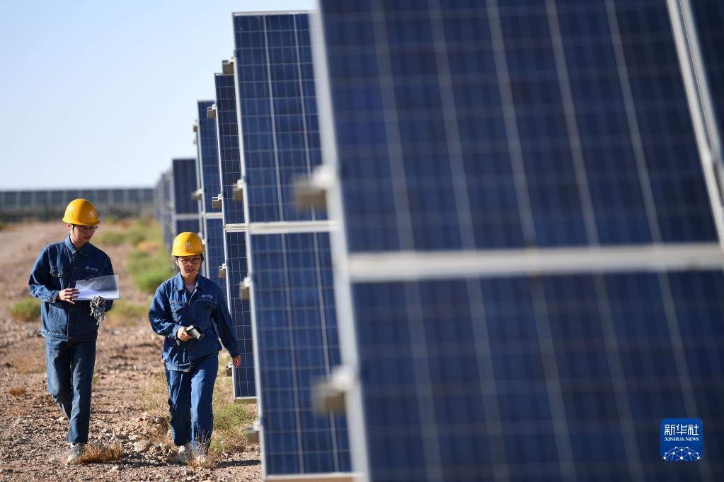华能集团西坡光伏电站工作人员李静(右)和同事在现场巡检(6月13日摄) 新华社记者 陈斌 摄