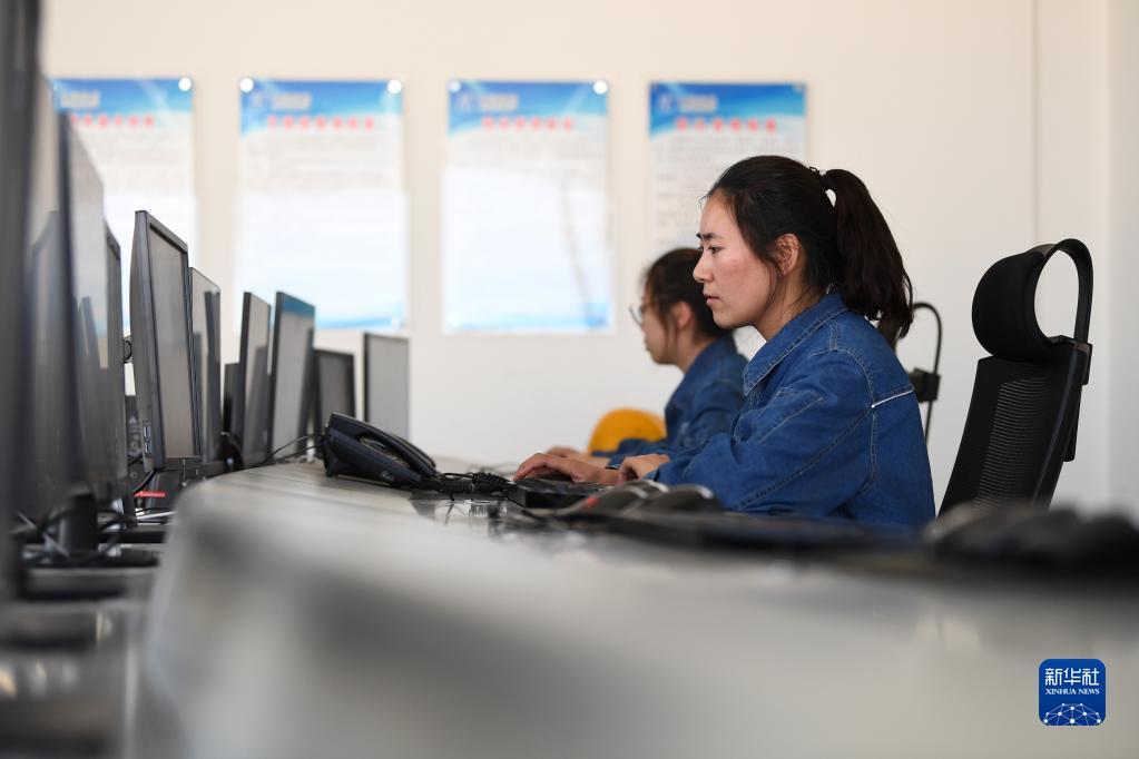 华能集团西坡光伏电站值班员包海霞(右)在中控室查看全景监控系统调试情况(6月13日摄) 新华社记者 陈斌 摄