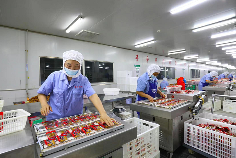梁平区奇爽食品有限公司工人在对豆干进行真空袋装。刘辉 摄