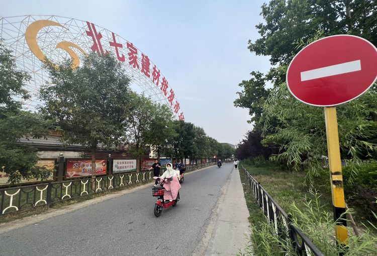 6月20日，行人通过北七家建材批发市场西门。