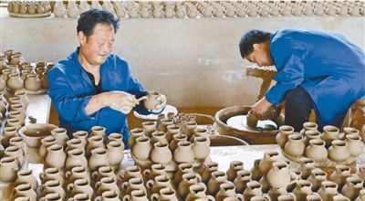 日前,在沙坝土陶艺工坊,市级非遗土陶艺传承人、陇南市首届乡土人才赵生桂(左),正在打磨土陶罐手工艺品。