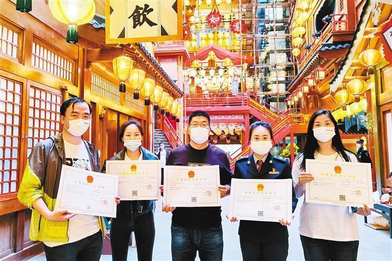 西安市市场监管局曲江分局工作人员将证照送到长安十二时辰主题街区商户们手中。 (记者 郝钟毓 摄)