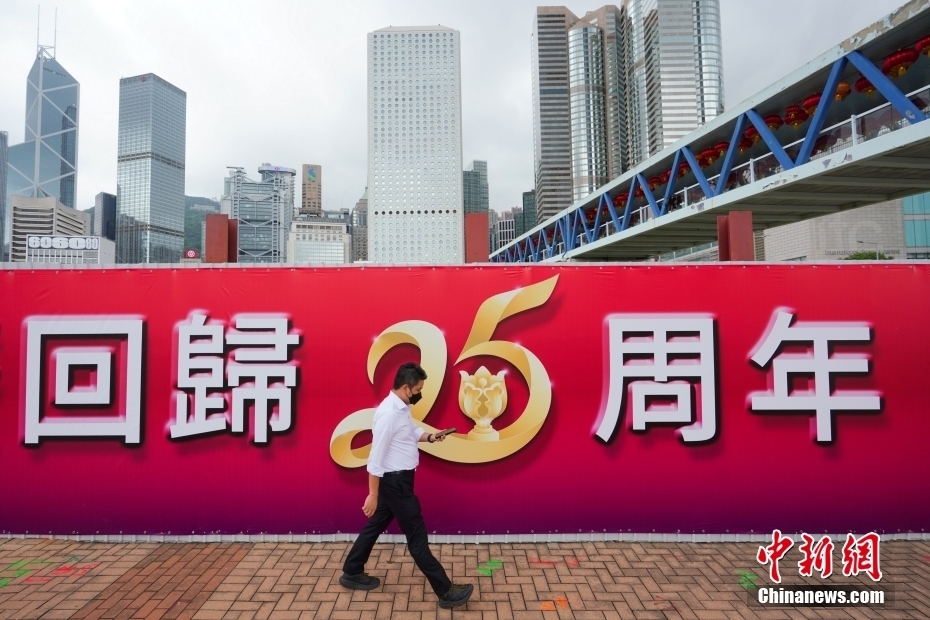 6月20日，香港中环街头，行人从庆祝香港回归25周年的大型标语前经过。随着香港回归祖国25周年纪念日临近，香港街头洋溢着浓浓的喜庆气氛。 中新社记者 张炜 摄
