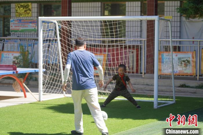 课余时间，师生两人在教室外的小足球场上踢球。　九美旦增　摄