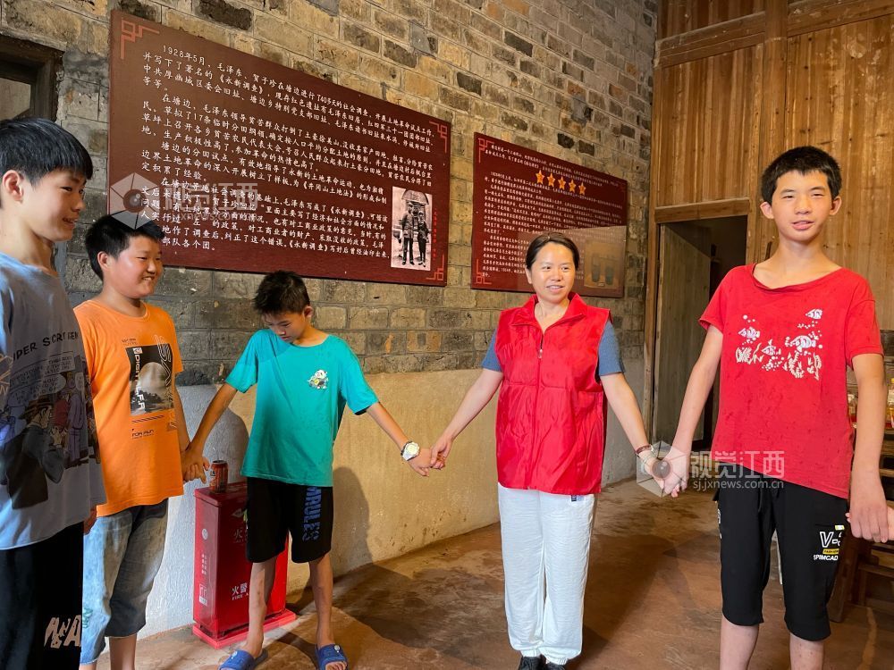 永新县沙市镇新时代文明实践志愿者正在为少先队员们讲述着曾发生在此处的红色故事。