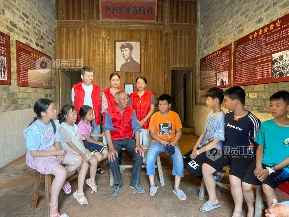 永新县沙市镇新时代文明实践志愿者正在为少先队员们讲述着曾发生在此处的红色故事。