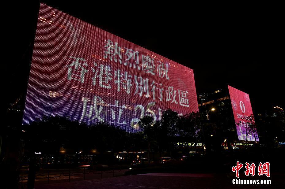 6月20日晚上，香港维多利亚港两旁的大厦灯光璀璨，尖沙咀中心的户外屏幕正播放庆回归标语。 中新社记者 李志华 摄