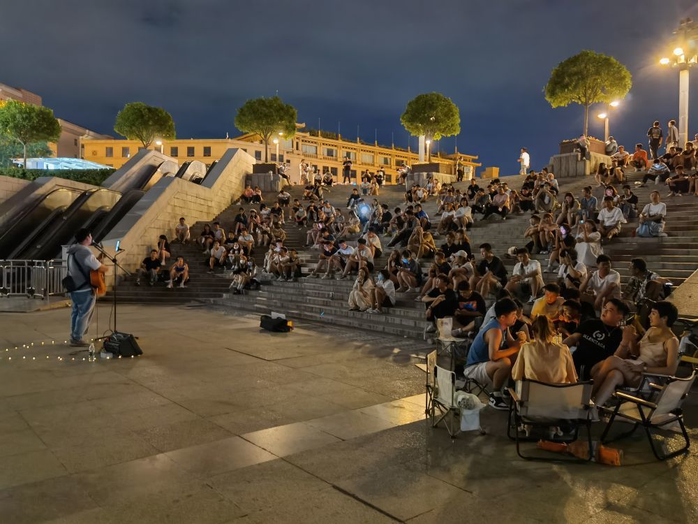 夜色中，钟楼广场吸引了很多听现场弹唱的观众。（新华社记者 张健 摄）