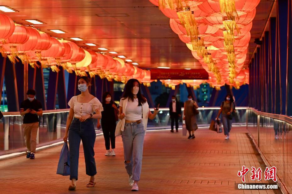 为庆祝香港回归祖国25周年，位于香港中环的一座天桥上挂满大红灯笼。6月23日傍晚时分，大红灯笼纷纷亮起，市民于大红灯笼下行走，感受喜庆气氛。 中新社记者 李志华 摄