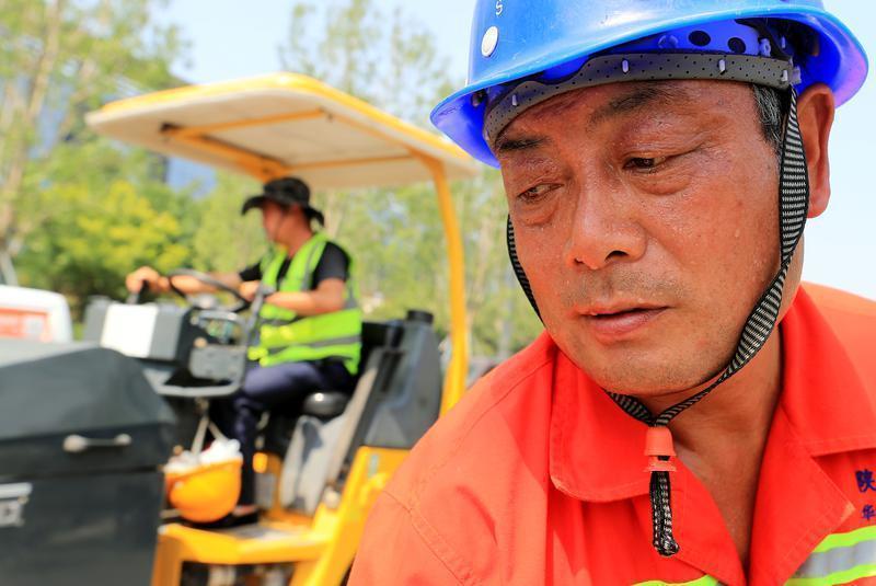 烈日下,正在鋪設道路的陝西華山路橋集團有限公司工人,汗流滿面,加緊