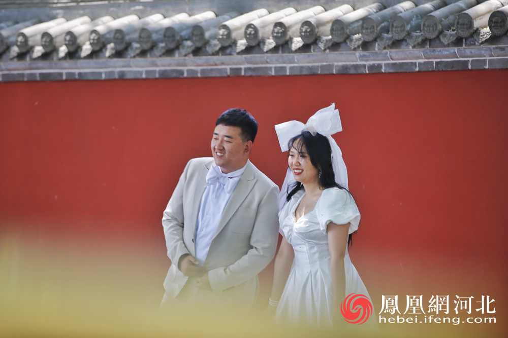 红墙青瓦前拍婚纱照的幸福“小两口”（网友投稿作品）