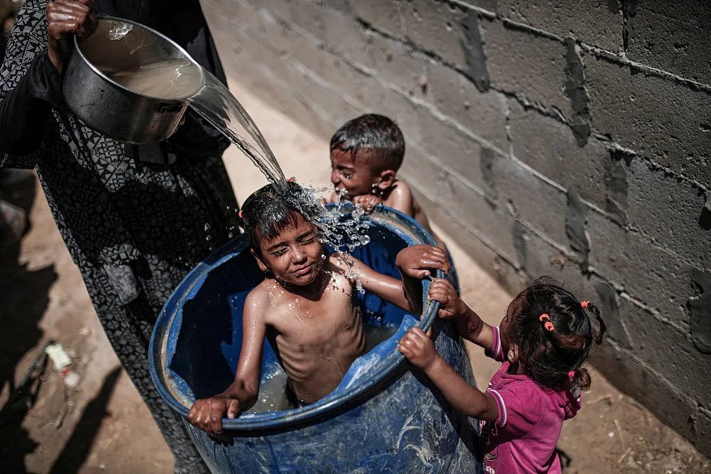 当地时间7月14日，加沙地带，当地遇高温天气，孩童户外洗澡降温。视觉中国供图
