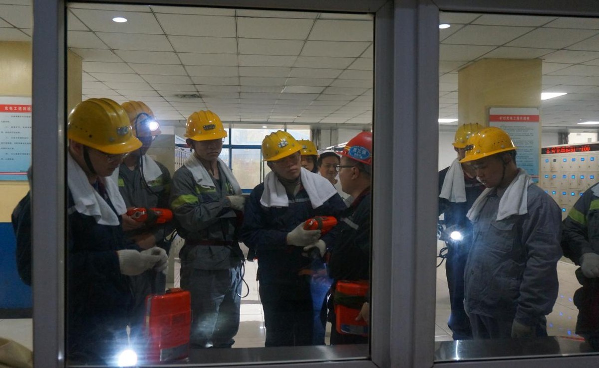 煤矿工作人员席文强为队员们说明头灯的佩戴方法