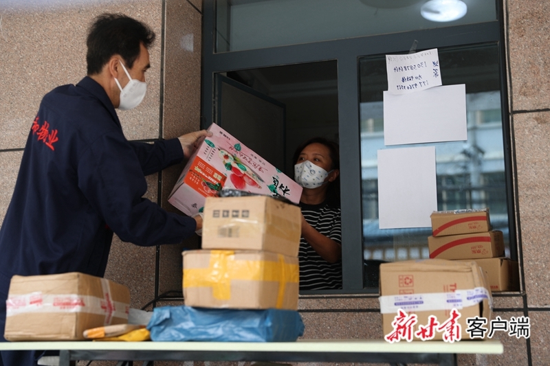 一位居民从小区志愿者手中接过快递员送来的包裹