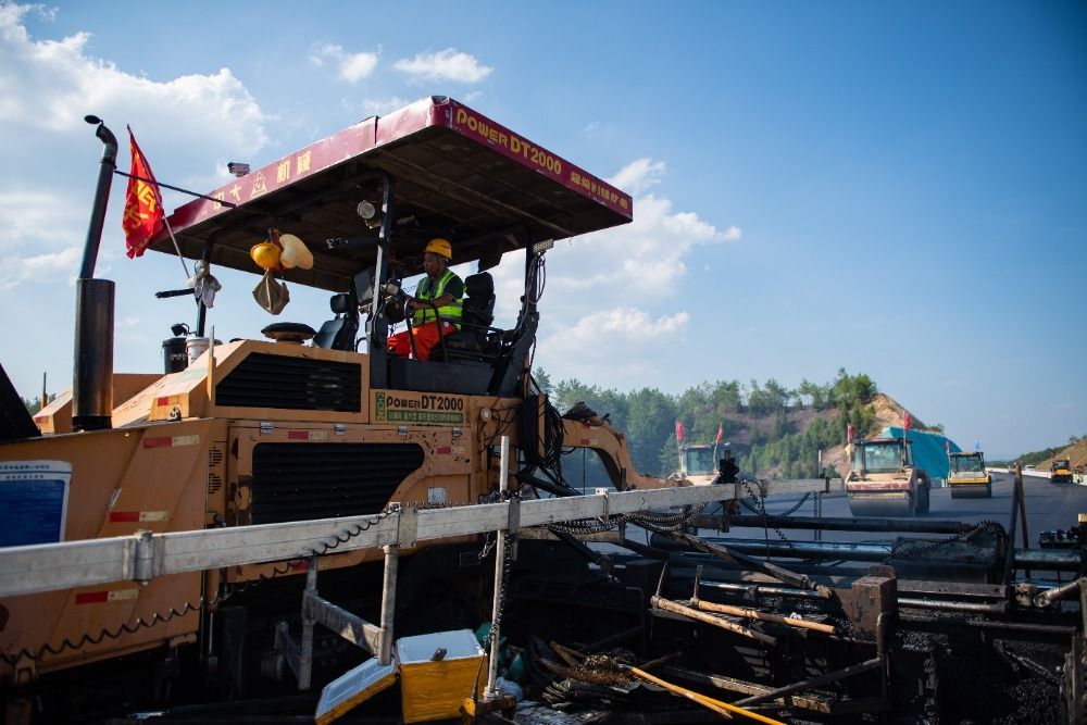 7月27日，工人在平益高速建设现场进行沥青上面层摊铺施工。