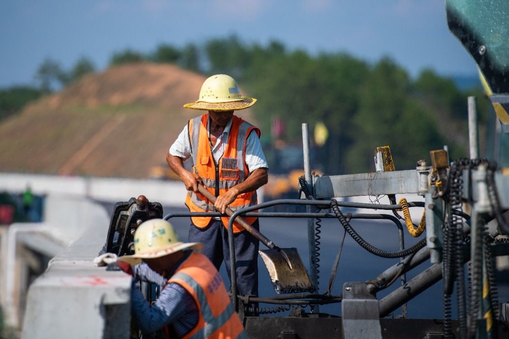 7月27日,工人在平益高速建设现场进行沥青上面层摊铺施工.